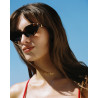 Lunettes de soleil forme papillon portées par une femme avec des montures marron et détails dorés sur les côtés